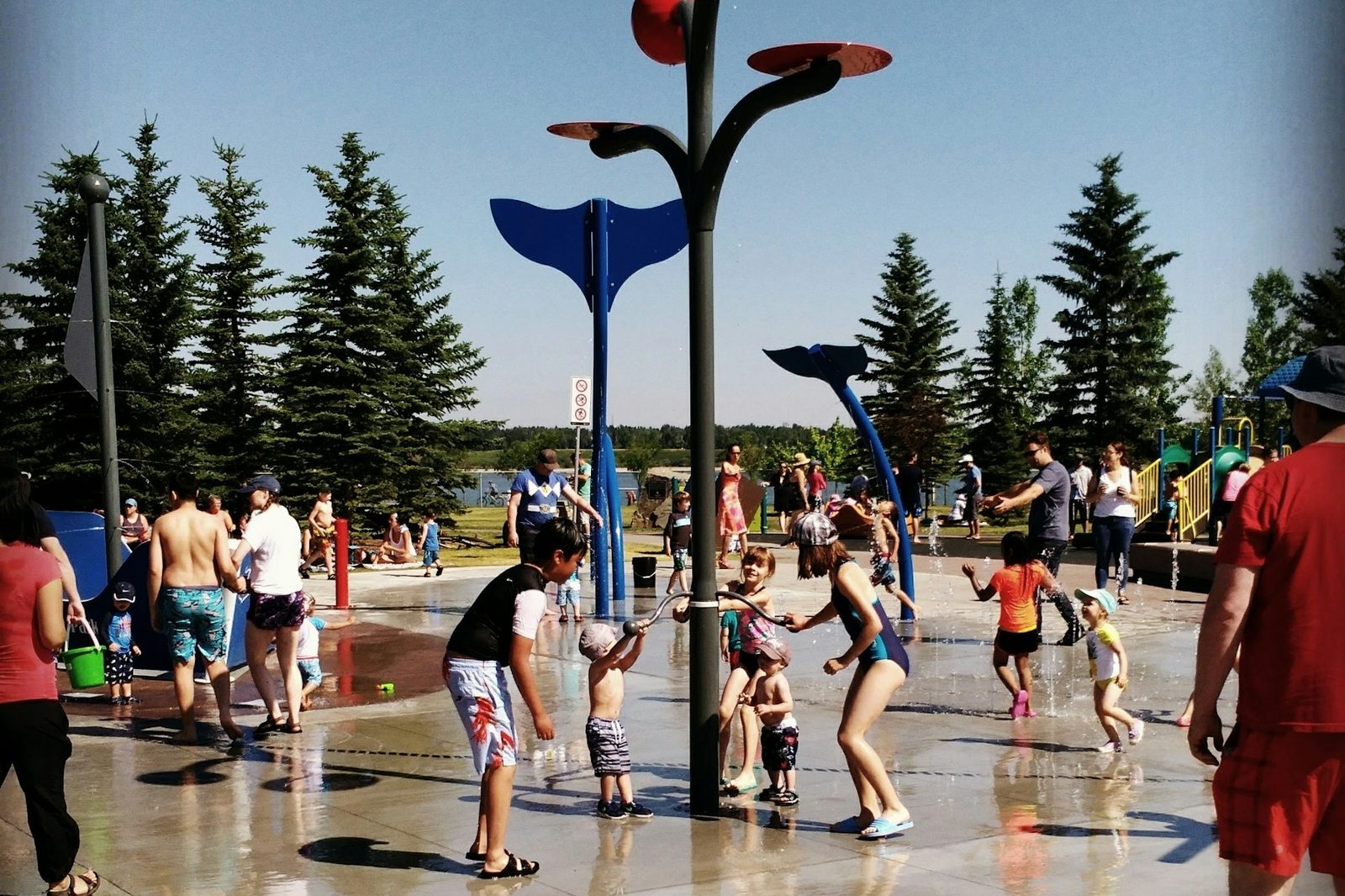 Children playing at a spray park splash pad on a sunny summer day